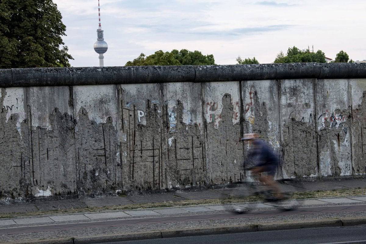 Günümüzde Berlin Duvarı'ndan kalan "anıt"ın önünden geçen bir bisikletli