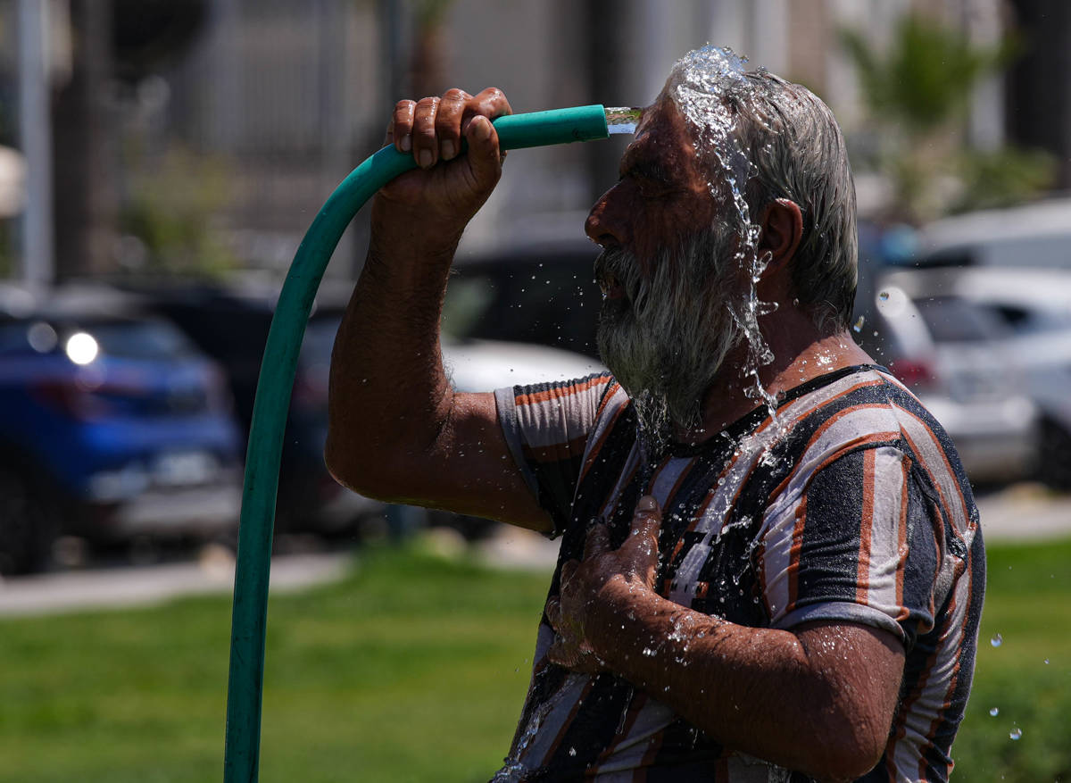 İzmir'de hortumla kendini serinletmeye çalışan bir yurttaş.