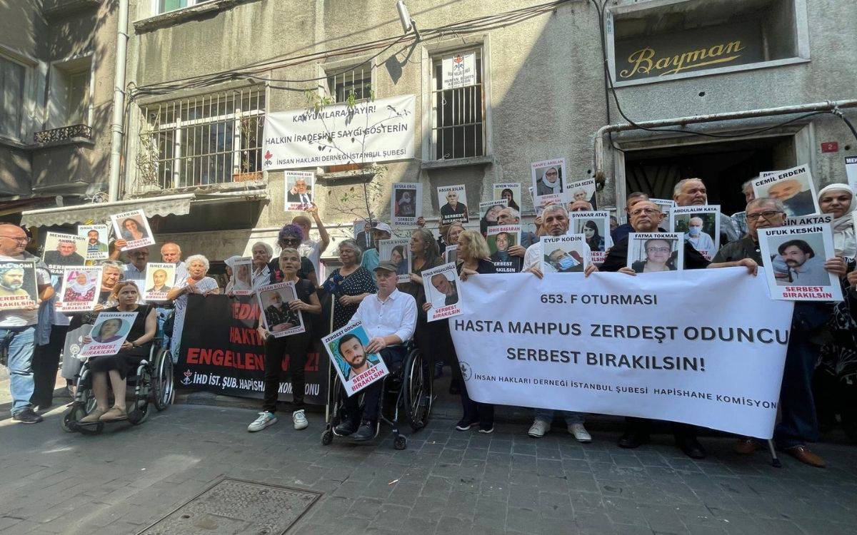 Fotoğrafta, İnsan Hakları Derneği İstanbul Şubesi Hapishane Komisyonu’nun düzenlediği 653. F Oturması sırasında çekilmiş bir görüntü yer alıyor. Etkinlikte bir grup insan, hasta mahpusların serbest bırakılmasını talep ediyor. Katılımcılar ellerinde hasta mahpusların fotoğraflarını taşıyor ve üzerlerinde "serbest bırakılsın" yazılı pankartlar bulunuyor.  Öndeki grup, büyük bir beyaz pankart tutuyor. Pankartta, "653. F Oturması - Hasta Mahpus Zerdeşt Oduncu Serbest Bırakılsın!" yazısı dikkat çekiyor. Sağ alt köşede ise pankartı düzenleyen İnsan Hakları Derneği İstanbul Şubesi Hapishane Komisyonu'nun adı yer almakta. Pankartın arkasında ve çevrede duran insanlar, hasta mahpusların fotoğraflarını tutarak dayanışmalarını ve taleplerini dile getiriyor.