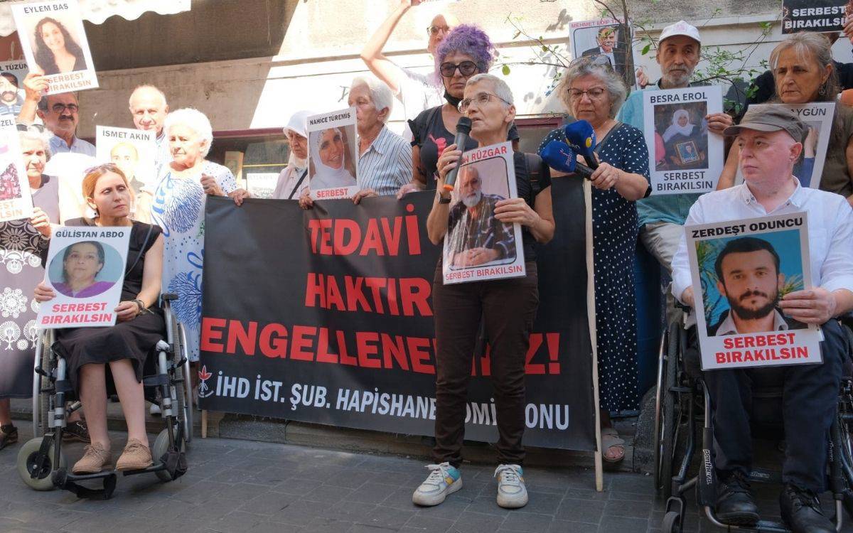 Bu fotoğraf, hasta ve engelli mahpusların serbest bırakılması talebiyle düzenlenen bir protesto gösterisini yansıtıyor. Gösteride bir grup insan, ellerinde cezaevinde bulunan hasta mahpusların fotoğraflarını tutuyor. Her bir fotoğrafın altında "Serbest Bırakılsın" ifadesi yer alıyor. Göstericiler arasında tekerlekli sandalyede bulunan kişiler de var, bu da hasta ve engelli mahpusların durumuna dikkat çekmeyi amaçlayan bir eylem olduğunu gösteriyor.