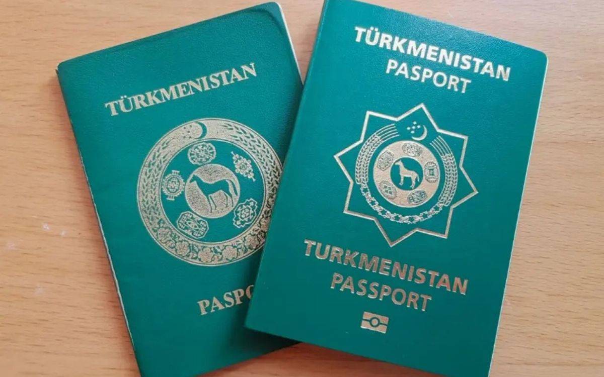 Bu görselde, Türkmen vatandaşlarına ait iki adet Türkmenistan pasaportu yan yana bir masa üzerinde duruyor. Pasaportlar yeşil kapaklı ve üzerinde Türkmenistan devletine ait amblemler yer alıyor. Pasaport kapaklarının üst kısmında "TÜRKMENISTAN" ve "PASPORT" ifadeleri büyük harflerle yazılmış. Sağdaki pasaportun altında biyometrik pasaport sembolü bulunuyor; bu da pasaportun uluslararası seyahat standartlarına uygun olduğunu gösteriyor. Amblemler, Türkmenistan’ın kültürel simgelerini içeriyor ve ortasında bir at figürü yer alıyor.