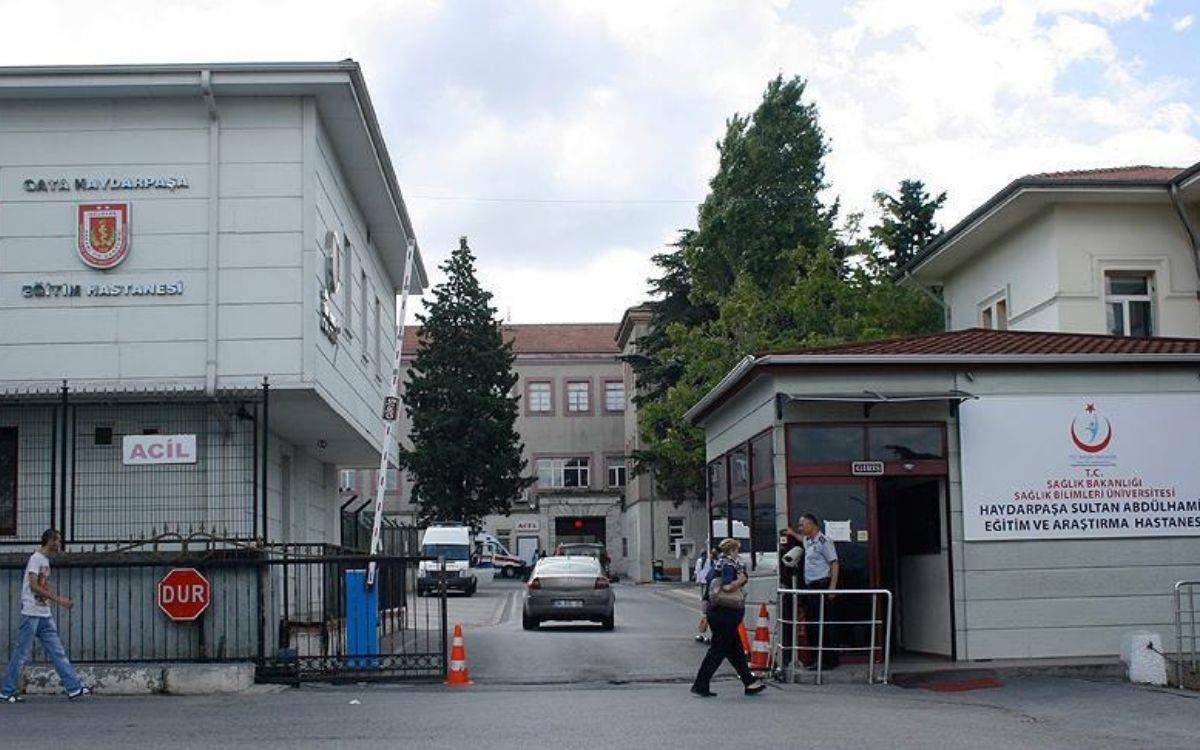 Bu fotoğrafta, İstanbul’daki Sultan Abdülhamid Han Eğitim ve Araştırma Hastanesi’nin ana giriş bölümü görülüyor. Hastanenin girişinde, üzerinde "T.C. Sağlık Bakanlığı Haydarpaşa Sultan Abdülhamid Eğitim ve Araştırma Hastanesi" yazan bir tabela bulunuyor. Sol tarafta ise eski adı olan "GATA Haydarpaşa Eğitim Hastanesi" tabelası yer almakta. Girişte acil servis tabelası da dikkat çekiyor. Çevrede güvenlik kulübesi ve bariyerler bulunuyor. Giriş yolunda çeşitli araçlar ve hastaneye gelen insanlar görülüyor. Hastane çevresinde ağaçlar ve klasik mimariye sahip hastane binaları fotoğrafa dingin bir görünüm katıyor.