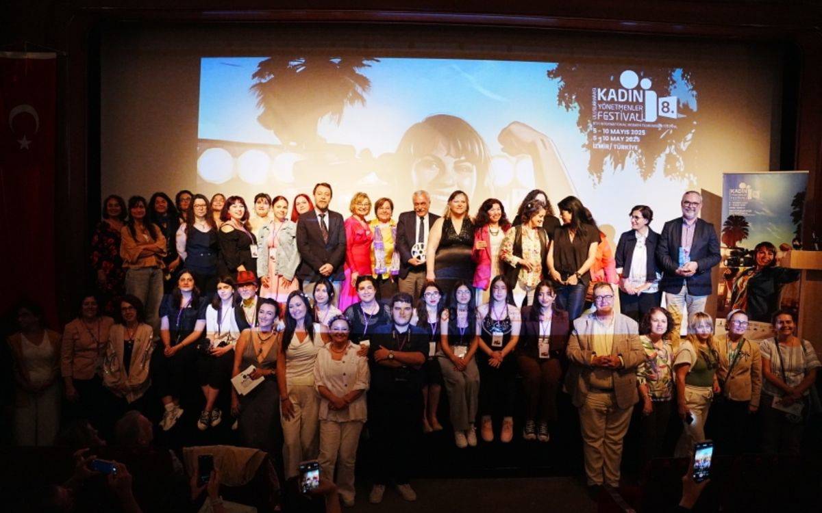 Fotoğraf, 8. Uluslararası Kadın Yönetmenler Festivali’nin açılış gecesinde sahnede toplu olarak poz veren katılımcıları gösteriyor.