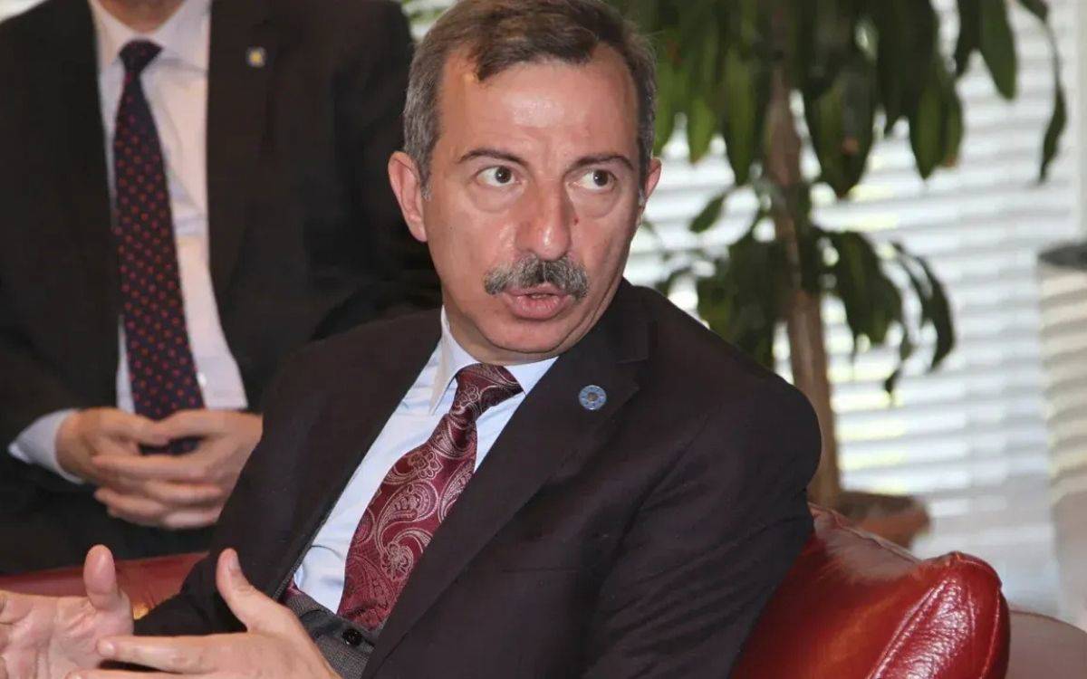 Fotoğraf, bir görüşme ya da toplantı ortamında çekilmiş gibi görünen ciddi ve resmi bir anı yansıtmaktadır.