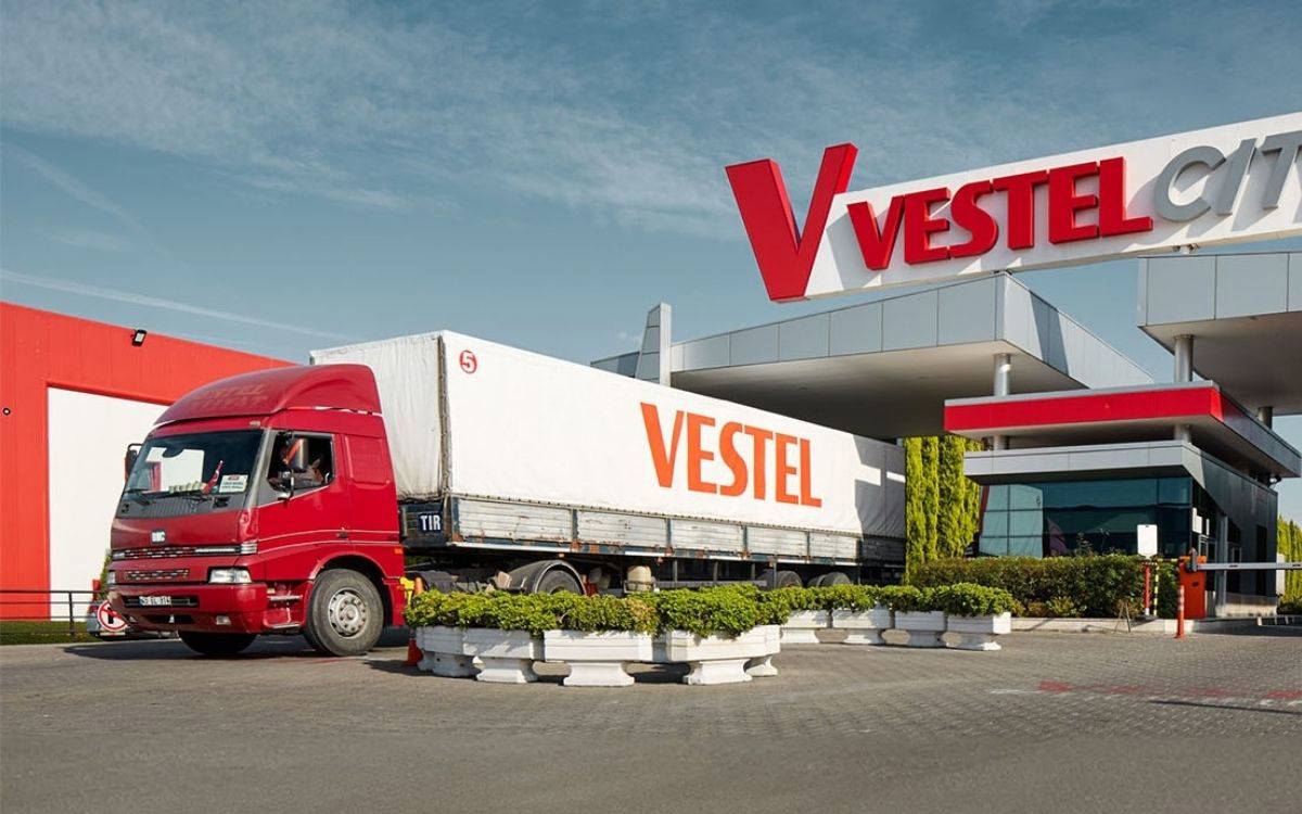 Fotoğraf, Vestel'in üretim tesislerinden biri olan Vestel City giriş kapısını ve önünde park etmiş büyük bir tırı göstermektedir