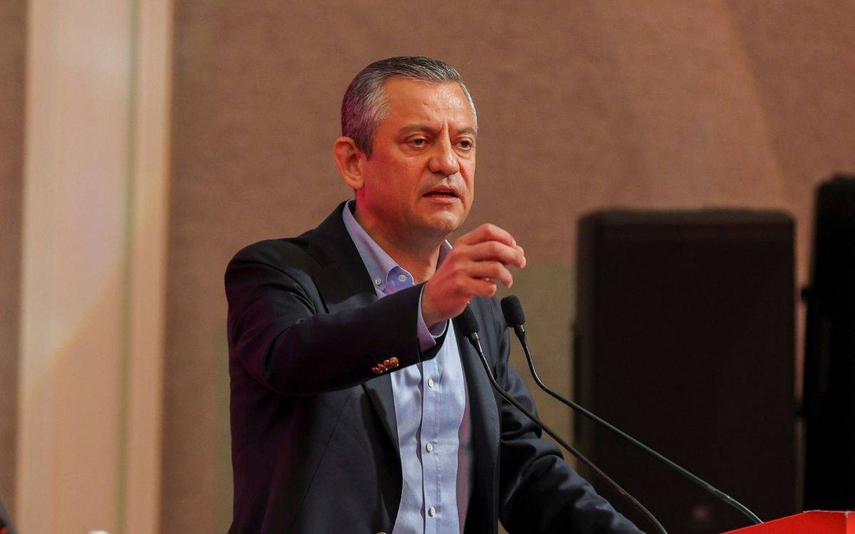 Fotoğrafta, bir erkek siyasetçi ya da konuşmacı kürsüde konuşma yaparken görülüyor. Üzerinde açık mavi gömlek ve lacivert ceket var. Sol eliyle bir hareket yaparak vurgu yapıyor, sağında bir mikrofon yer alıyor. Yüz ifadesi ciddi ve kararlı; muhtemelen önemli bir mesaj verirken veya bir soruna dikkat çekerken çekilmiş.