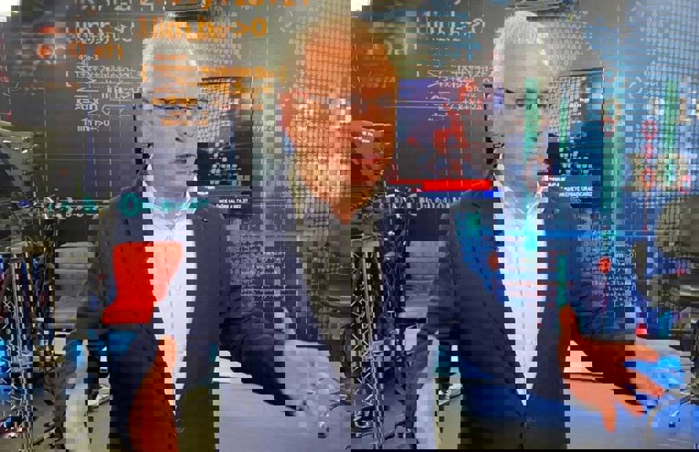 Fotoğrafta Merdan yanardağ lacivert ceket giymiş ve gözlüklü. Açıklama yapıyor gibi.