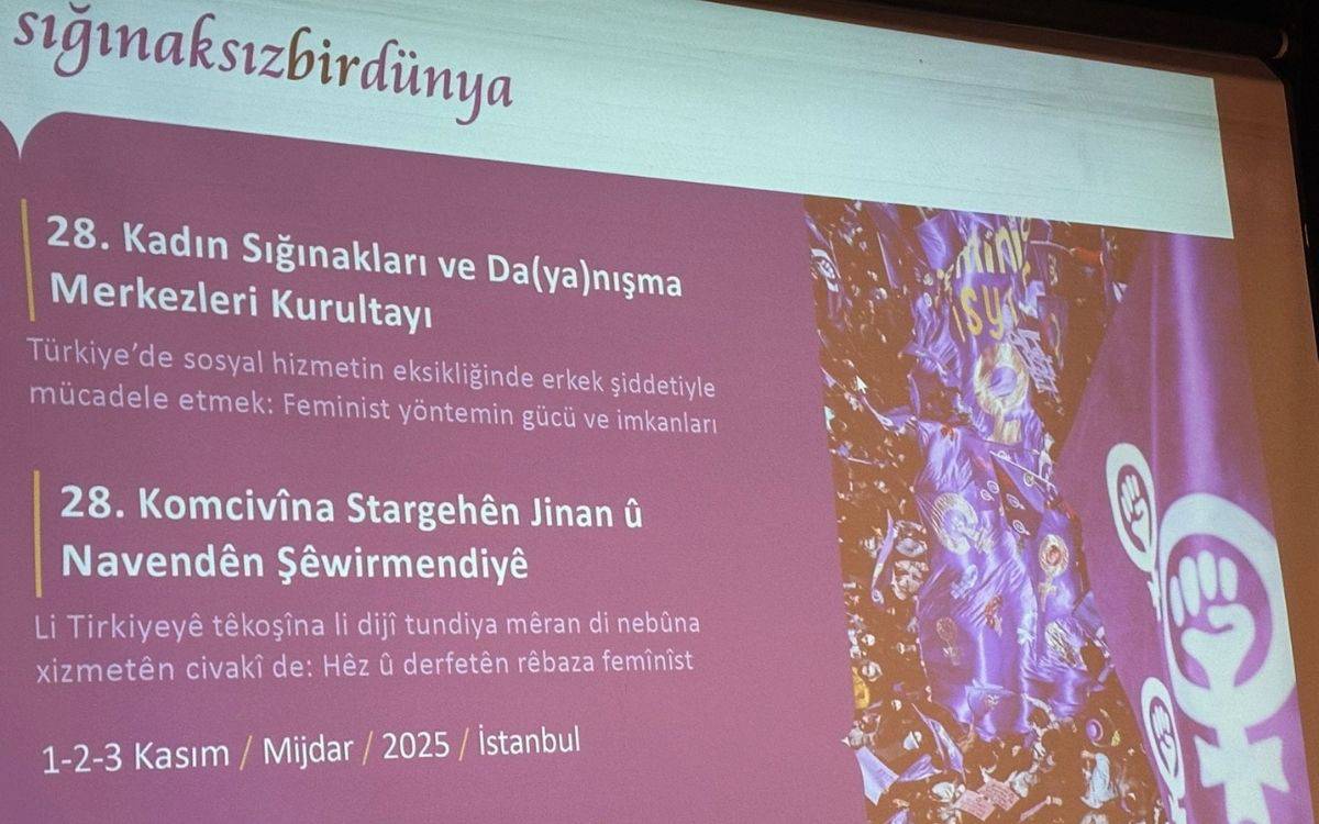 u görsel, 28. Kadın Sığınakları ve Danışma Merkezleri Kurultayı'nın tanıtıldığı bir sunum ekranını gösteriyor. Ekranda, kurultayın ismi ve konusu yer almakta: 28. Kadın Sığınakları ve Danışma Merkezleri Kurultayı Türkiye’de sosyal hizmetin eksikliğinde erkek şiddetiyle mücadele etmek: Feminist yöntemin gücü ve imkanları Alt kısmında, aynı etkinliğin Kürtçe olarak da yazılı olduğu bir bölüm var: 28. Komcivîna Stargehên Jinan û Navendên Şewirmendiyê Li Tirkîyeyê têkoşîna li dijî tundiya mêrân di nebûna xizmetên civakî de: Hêz û derfetên rêbaza feminist Ekranda ayrıca, etkinlikle ilişkili mor renkli bayraklar ve feminist simgeler (kadın simgesi ve yumruk işareti) yer almakta. Bu görsel, feminist bir etkinliğin duyurusu olarak tasarlanmış ve genellikle toplumsal cinsiyet eşitliği ve kadına yönelik şiddetle mücadeleye dair mesajlar içeren bir atmosferi yansıtıyor.