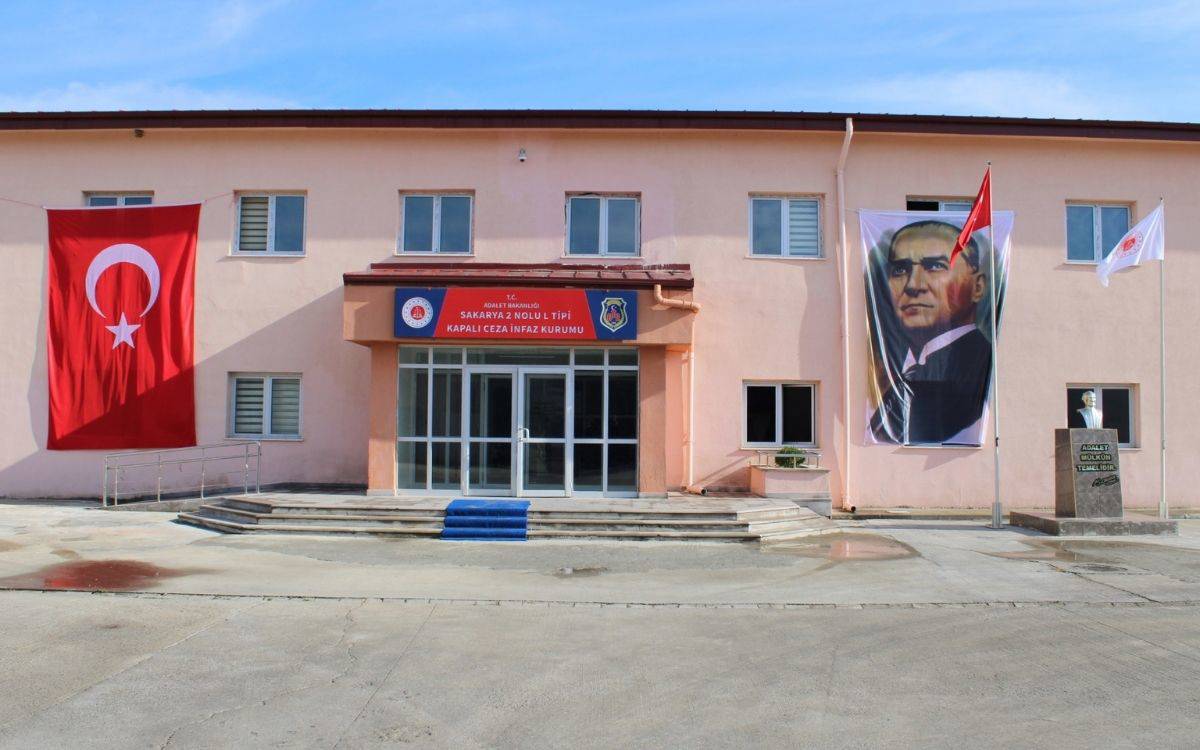 Büyük bir binada atatürk fotoğrafı ve kırmızı beyaz renkli Türkiye bayrağı var.