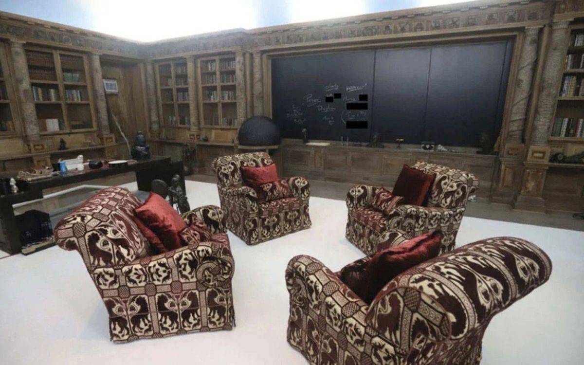 Bir odada renkli koltuklar ve syah bir tahta var. Tahtanın üzerinde tebeşirle beyaz renkte yazılar var.