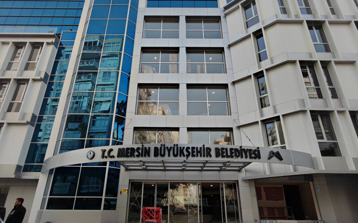 Fotoğraf Mersin Büyükşehir Belediyesi binasının girişi gözüküyor.