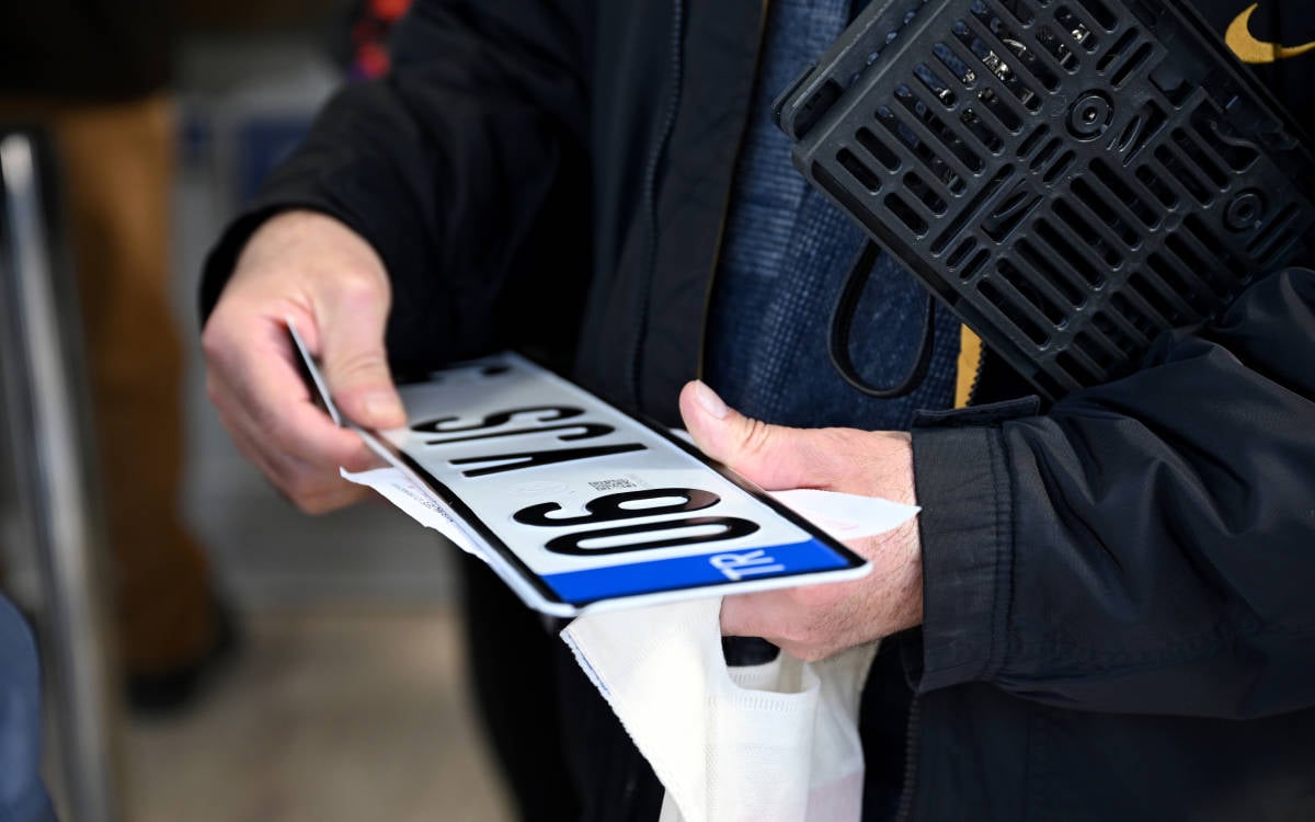 Fotoğrafta Ankara'dan. Plakasını yenileyen bir kişi elinde tuttuğu plakaya bakıyor.