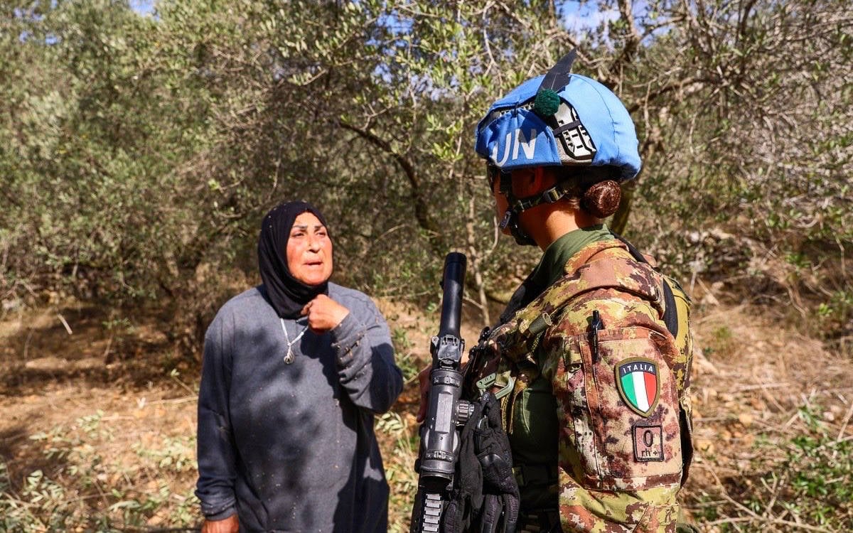 Fotoğrafta İtalyan bir UNIFIL askeri, Güney Lübnan'daki bir zeytin bahçesinde bir kadınla konuşuyor