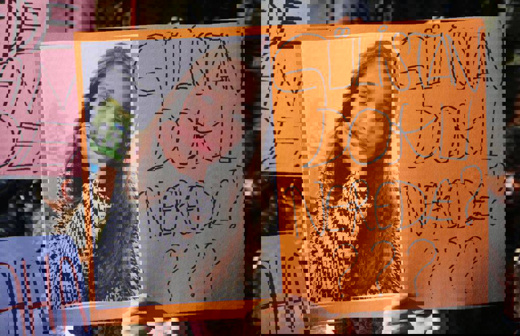 Görüntü bozulmuş görünüyor; fotoğrafın üstünde yoğun yeşil yatay çizgiler var. Buna rağmen ortada bir kadın portresi ve sağ tarafta “GÜLİSTAN DOKU” yazısı seçiliyor. Görsel, bir afiş ya da pankart gibi duruyor.