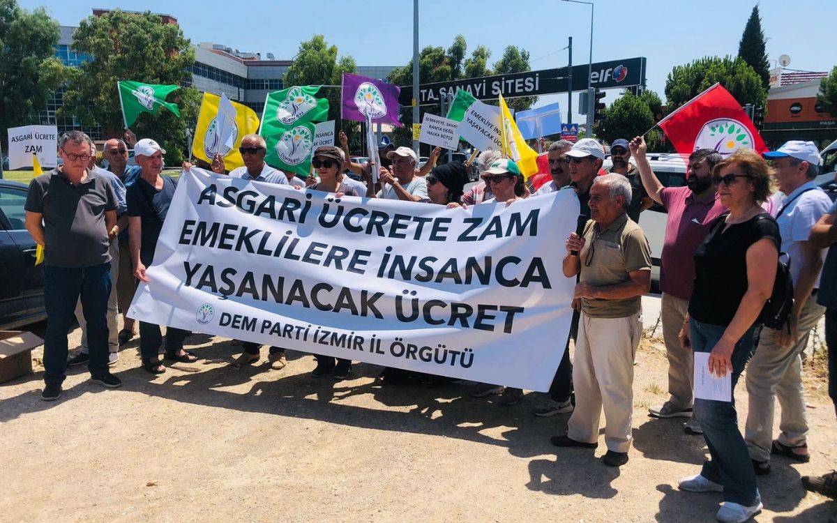 Bu fotoğrafta, bir grup insan, dış mekanda toplanmış ve bir protesto ya da basın açıklaması düzenliyor. Ellerinde büyük bir pankart taşıyorlar. Pankartta "Asgari Ücrete Zam, Emeklilere İnsanca Yaşanacak Ücret" yazıyor ve altında "DEM PARTİ İZMİR İL ÖRGÜTÜ" ifadesi yer alıyor. Katılımcılar arasında kadınlar ve erkekler bulunuyor, ve bazıları ellerinde farklı renklerde bayraklar taşıyor. Arkadaki bayrakların üzerinde de parti sembolleri yer alıyor. İnsanlar güneşli bir havada toplanmış, bu da etkinliğin açık alanda, muhtemelen bir meydan ya da sokakta gerçekleştiğini gösteriyor. Arka planda bazı binalar ve ağaçlar da görülebiliyor. Ortam, emekle ilgili taleplerin dile getirildiği bir protesto havasında.