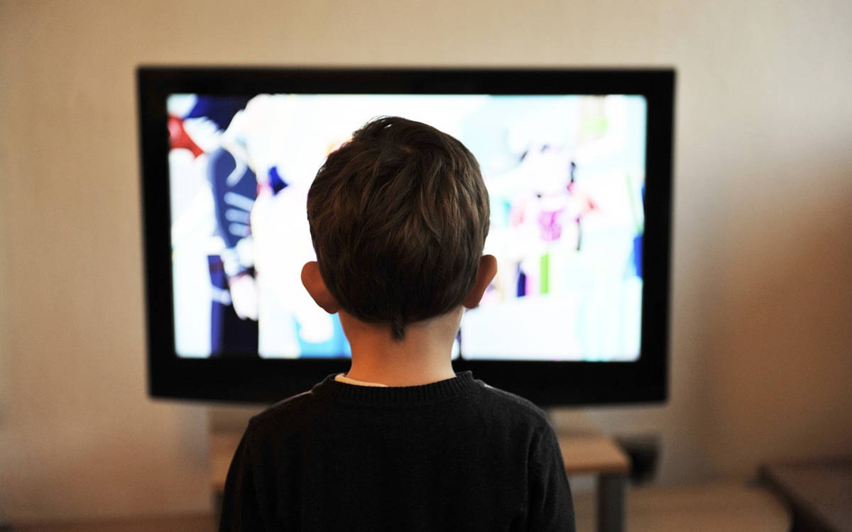 Görselde, soyut ve sanatsal bir kompozisyon yer alıyor. Bir tekerlekli sandalyede oturan bir kişi, insan bedeni yerine eski tip bir televizyon ekranına sahip. Televizyonun ekranında renkli çizgiler görülüyor, bu da yayın yapılmadığı anlamına geliyor. Kişi gri tonlarda kıyafetler giymiş ve spor ayakkabıları var. Arka planda parlak sarı, yeşil ve turkuaz renklerden oluşan geometrik desenler bulunuyor. Sol üst köşede "On Air" (Yayında) yazan bir tabela var. Ayrıca sol altta bir film kamerası görülüyor ve kameranın çekim yaptığı izlenimi veriliyor. Sağ üstte birkaç insan silüeti, sosyal bir ortamı temsil eder şekilde yer alıyor. Görsel, medya, televizyon ve engellilik gibi temalara dair bir mesaj içeren, dikkat çekici ve modern bir sanat çalışmasını yansıtıyor.