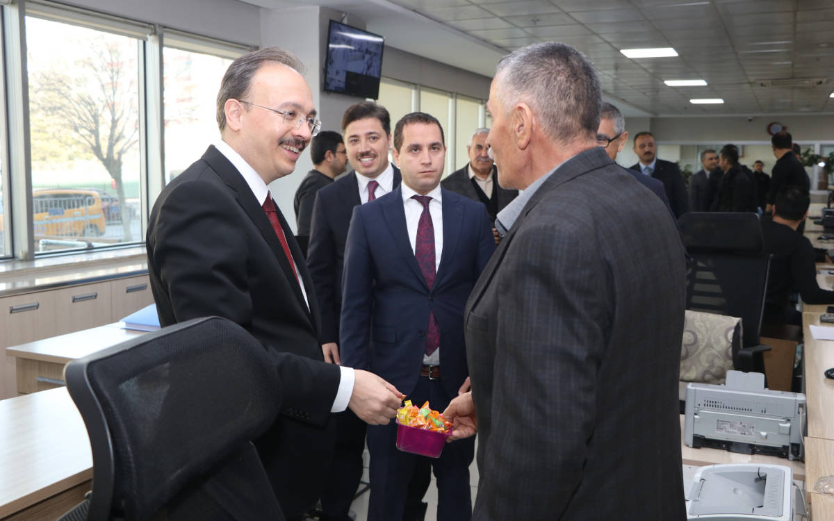 Fotoğrafta Siirt Valisi ve kayyımı Kemal Kızılkaya var. Kızılkaya, ofis ortamında bir kişiyi ziyaret ediyor. Kızılkaya'nın yüzü gülümsüyor. Arkada takım elbiseli yetkililer var.