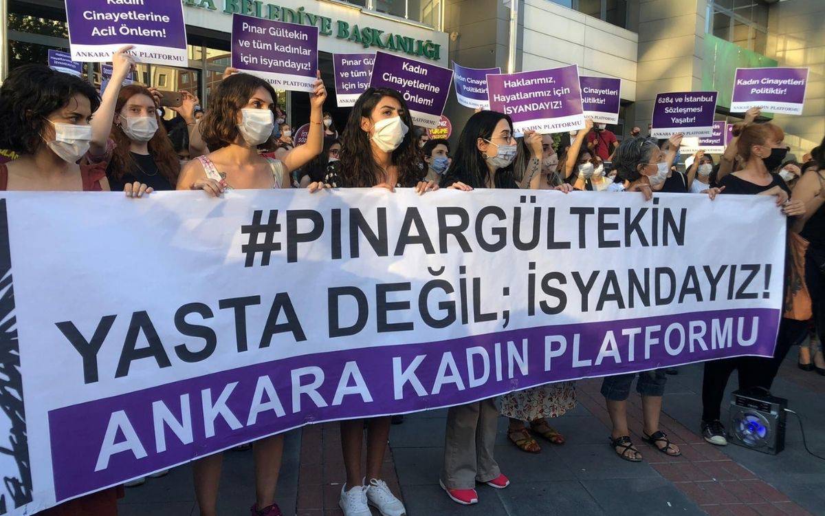 Bu fotoğrafta, bir grup kadın aktivist Ankara'da bir protesto düzenliyor. Kalabalık, çeşitli pankartlar ve afişler taşıyor. En önde büyük bir pankart üzerinde "#PINAR GÜLTEKİN YASTA DEĞİL; İSYANDAYIZ!" yazıyor ve pankartın alt kısmında "ANKARA KADIN PLATFORMU" ibaresi yer alıyor.