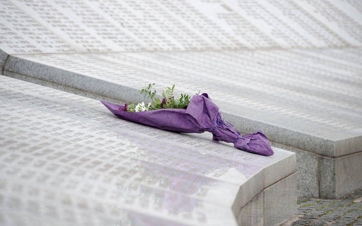Fotoğrafta, üzerine çok sayıda ismin yazılı olduğu büyük bir anıt ya da mezar taşını andıran mermer yüzeyler görülüyor. Bu yüzeylerin üzerine mor kâğıda sarılmış bir çiçek demeti bırakılmış. Çiçek buketinin içinde beyaz papatyalar ve birkaç yeşil yapraklı dal yer alıyor. Buket gelişi güzel bırakılmış, ancak özenle hazırlanmış olduğu belli.