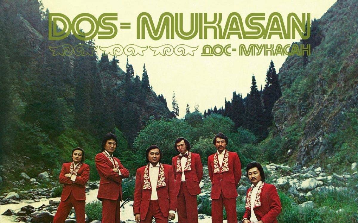 Görselde, dağlık ve yemyeşil bir vadide çekilmiş bir fotoğraf yer alıyor. Arka planda yüksek kayalıklar, sık çam ağaçları ve kıvrılarak akan bir dere görünüyor. Doğa oldukça huzurlu, serin ve bozulmamış bir atmosfer sunuyor.  Ön planda ise altı kişilik bir müzik grubu bulunuyor. Hepsi kırmızı, takım elbise tarzında, geleneksel motiflerle süslenmiş ceketler giymiş. Beyaz gömlekleri ve uyumlu kırmızı pantolonlarıyla sahne kostümüne benzer bir görünüm sergiliyorlar. Grup üyeleri poz verirken sakin, özgüvenli ve samimi bir duruşları var.