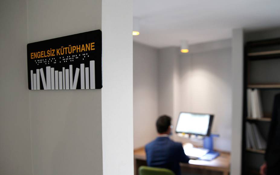 Fotoğraf: Kayseri’de Talas Belediyesi'nin kütüphanesinde bir oda. Odada görme ve işitme engelliler için Braille klavyeli bilgisayarlar ve büyüteç ekran var. Bilgisayar başında da arkasını dönük bir kişi oturuyor.