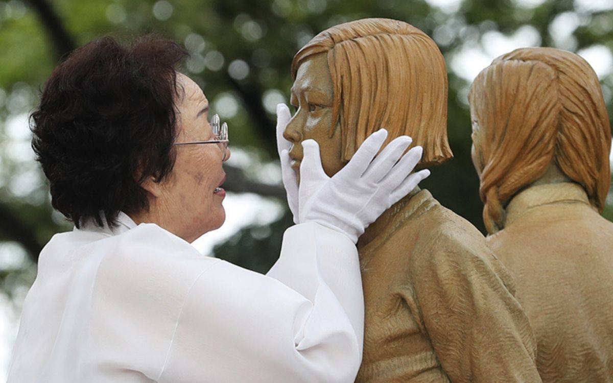 “Hayatta kalan bir teselli kadını olan Lee Yong-soo, 14 Ağustos’ta Seul’ün Jung-gu bölgesindeki Joseon Shingung yakınlarında düzenlenen açılış töreninde bir teselli kadını heykelini okşuyor.”